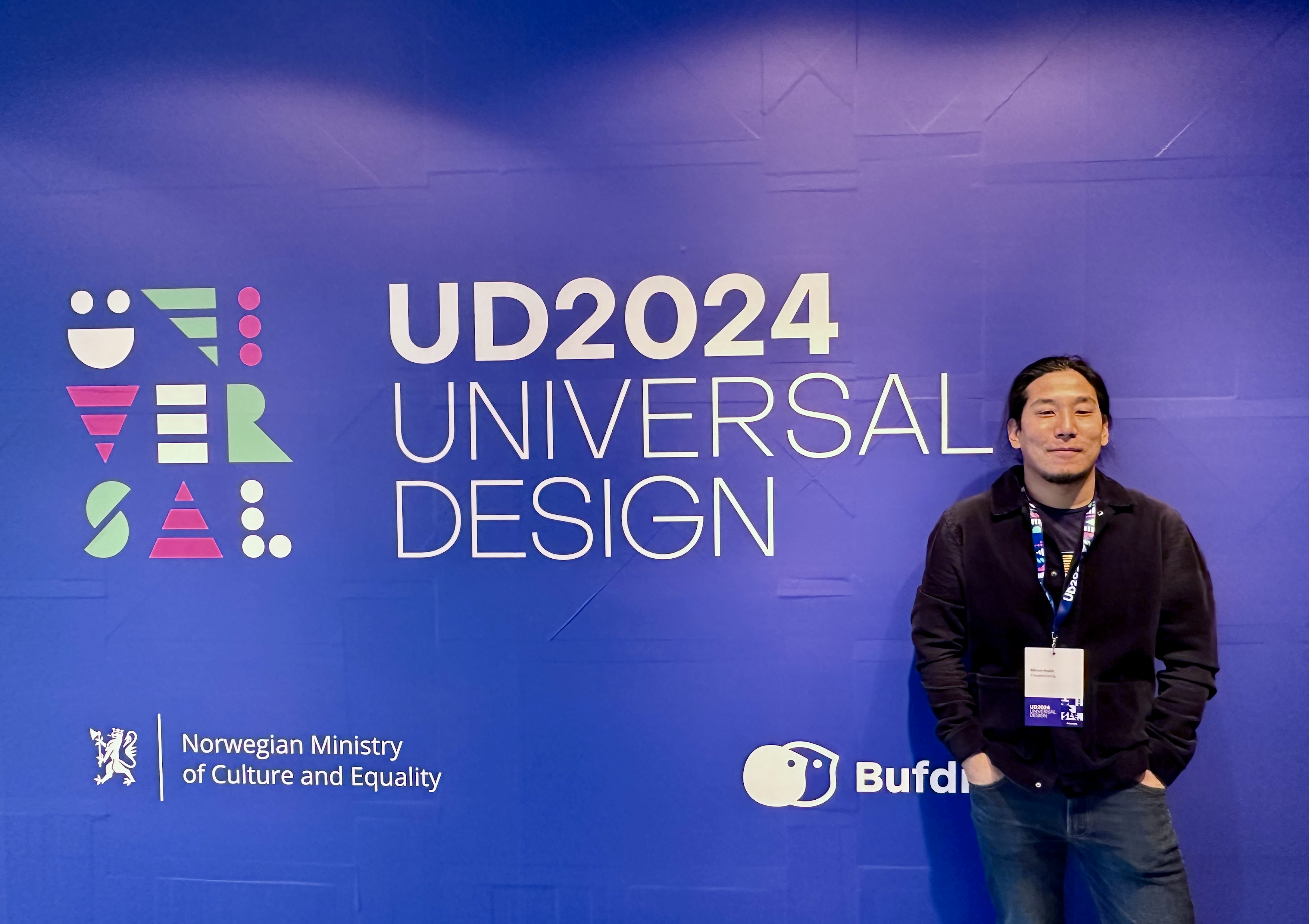 A person infront of a purple-blue background with texts, UD2024 Universal design